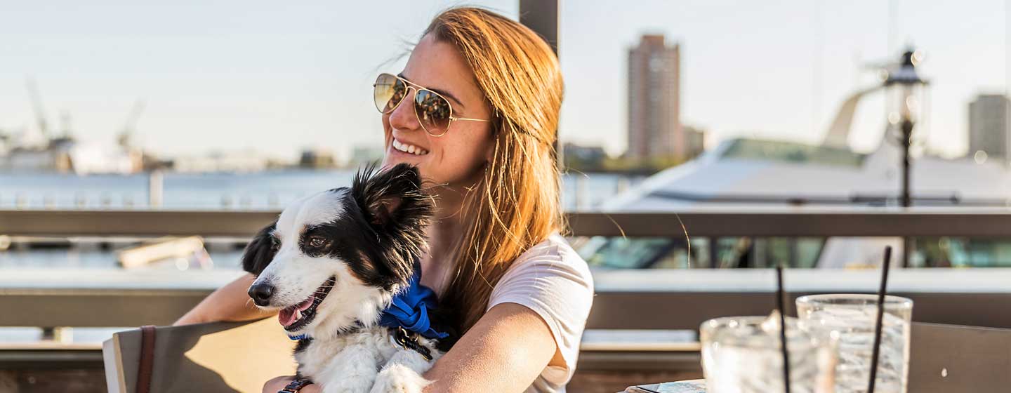 Woman holding dog outside. 