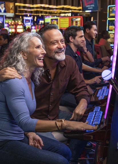 Couple enjoying playing slots together at a casino.