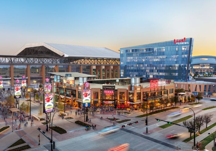 Outside of beautiful Texas Live!, featuring a tall mirrored Live! by Loews hotel that reflects structures and skies.