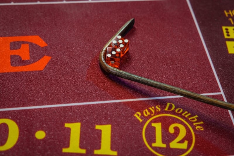 Image of a craps table felt and the rake and dice
