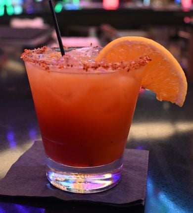 image of an orange margarita in a cocktail glass with an orange slice garnish