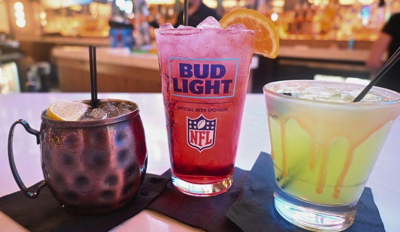 image of a cocktail in a mule glass, a red cocktail in a pint glass with an orange garnish, and a green cocktail in a short glass with caramel drizzle at sports & social inside live casino louisiana