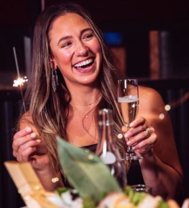 image of a woman holding a sparkler and toasting with a glass of champagne for new years eve at luk fu louisiana