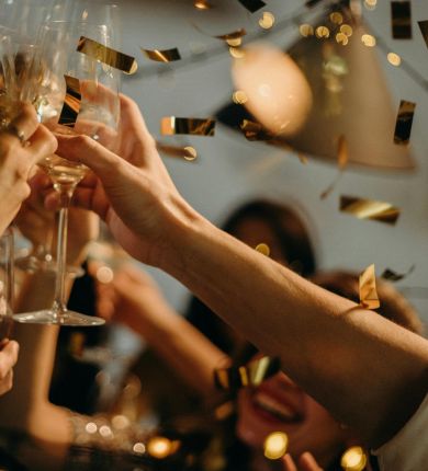 image of people cheering glasses and throwing confetti