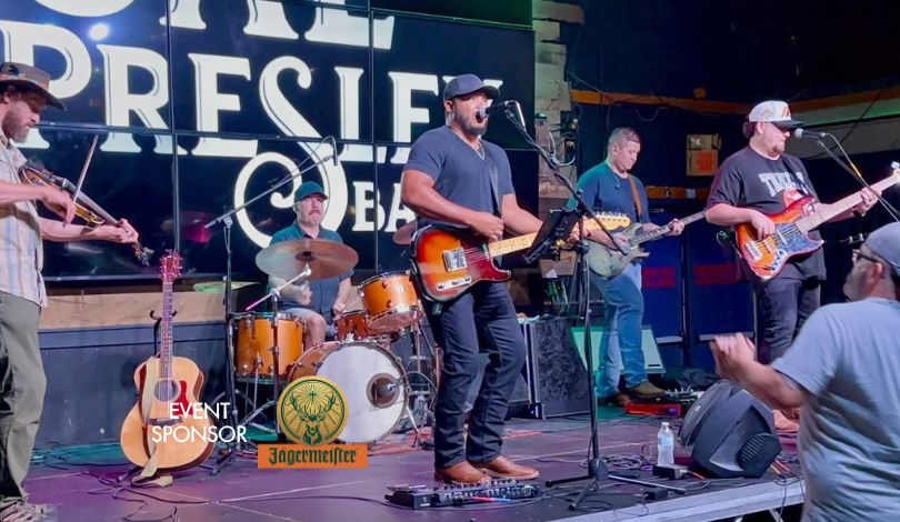 image of 5 people on a stage playing instruments and people in the crowd in front of them