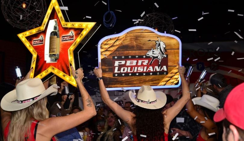 image of girls in cowboy hats holding PBR Louisiana signs with confetti in the air