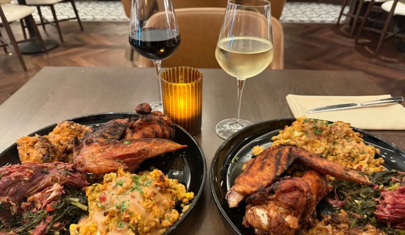 image of two wine glasses with red wine and white wine, a small brown candle, and two plates of thanksgiving food at ridotto grand cafe