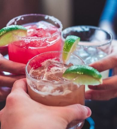 image of three people holding margarita glasses with lime garnishes