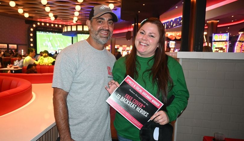 image of man in grey shirt and woman in green shirt standing in Sports & social louisiana holding a certificate for a complimentary VIP booth at PBR louisiana