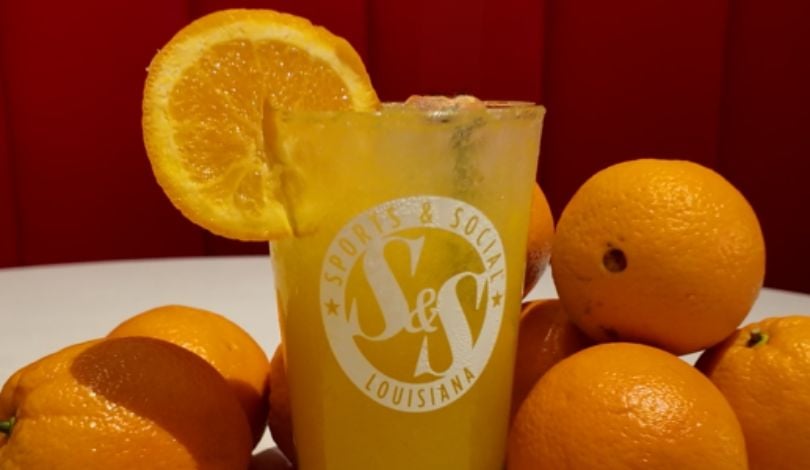 photo of an orange crush drink in a sports & social pint glass with orange fruits around it
