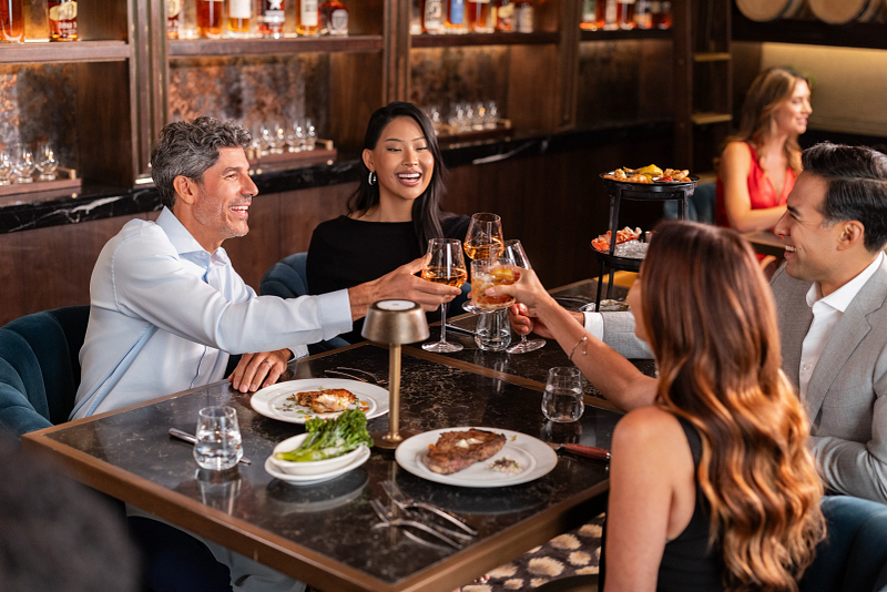 Two couples who are having dinner at The Prime Rib and are toasting their drinks.