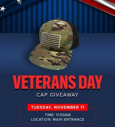 Veterans Day Cap Giveaway. Army green/camo baseball cap with an American flag on it in front of a dark blue background.