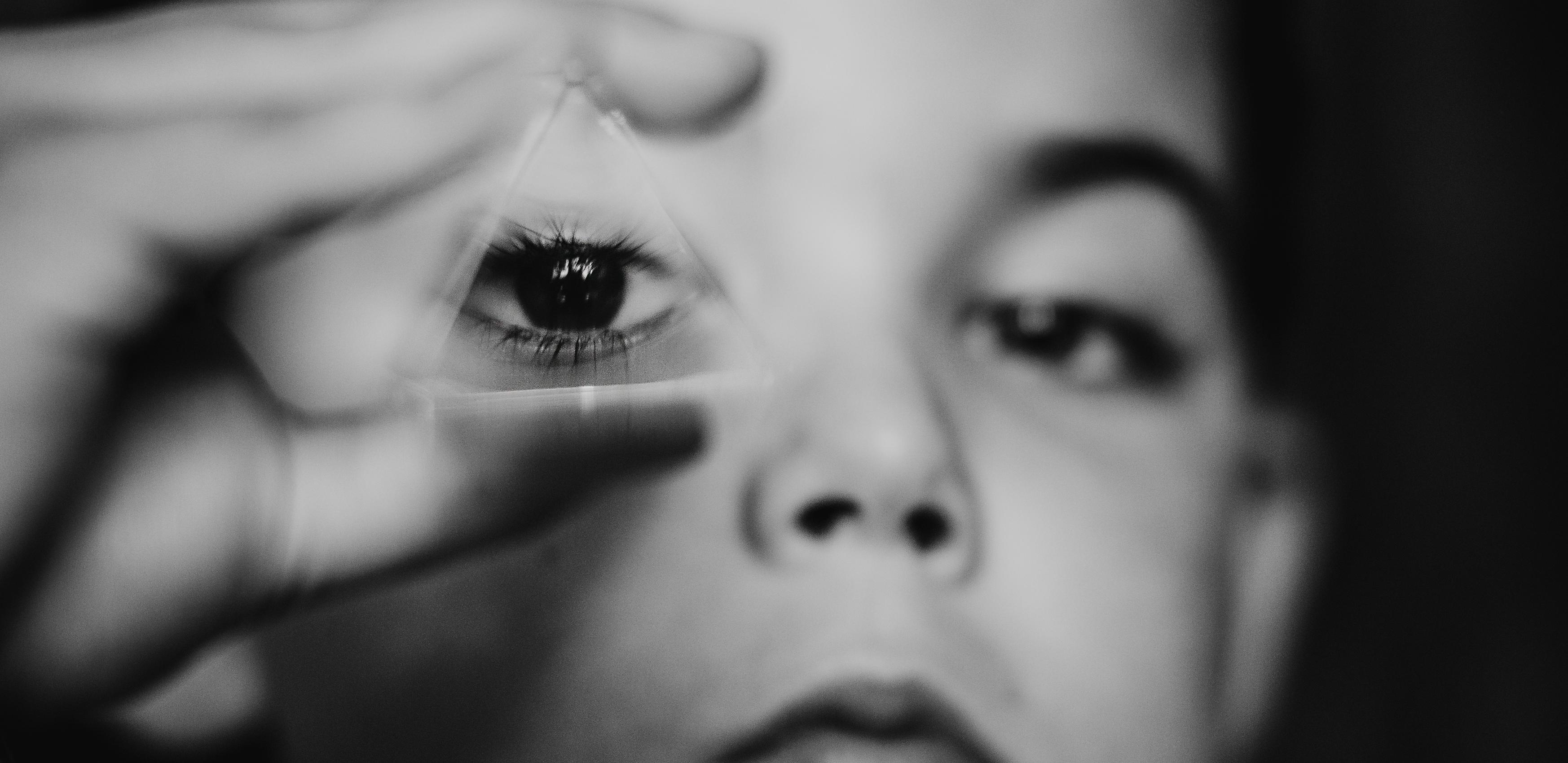 Boy looking through glass prism with one eye.