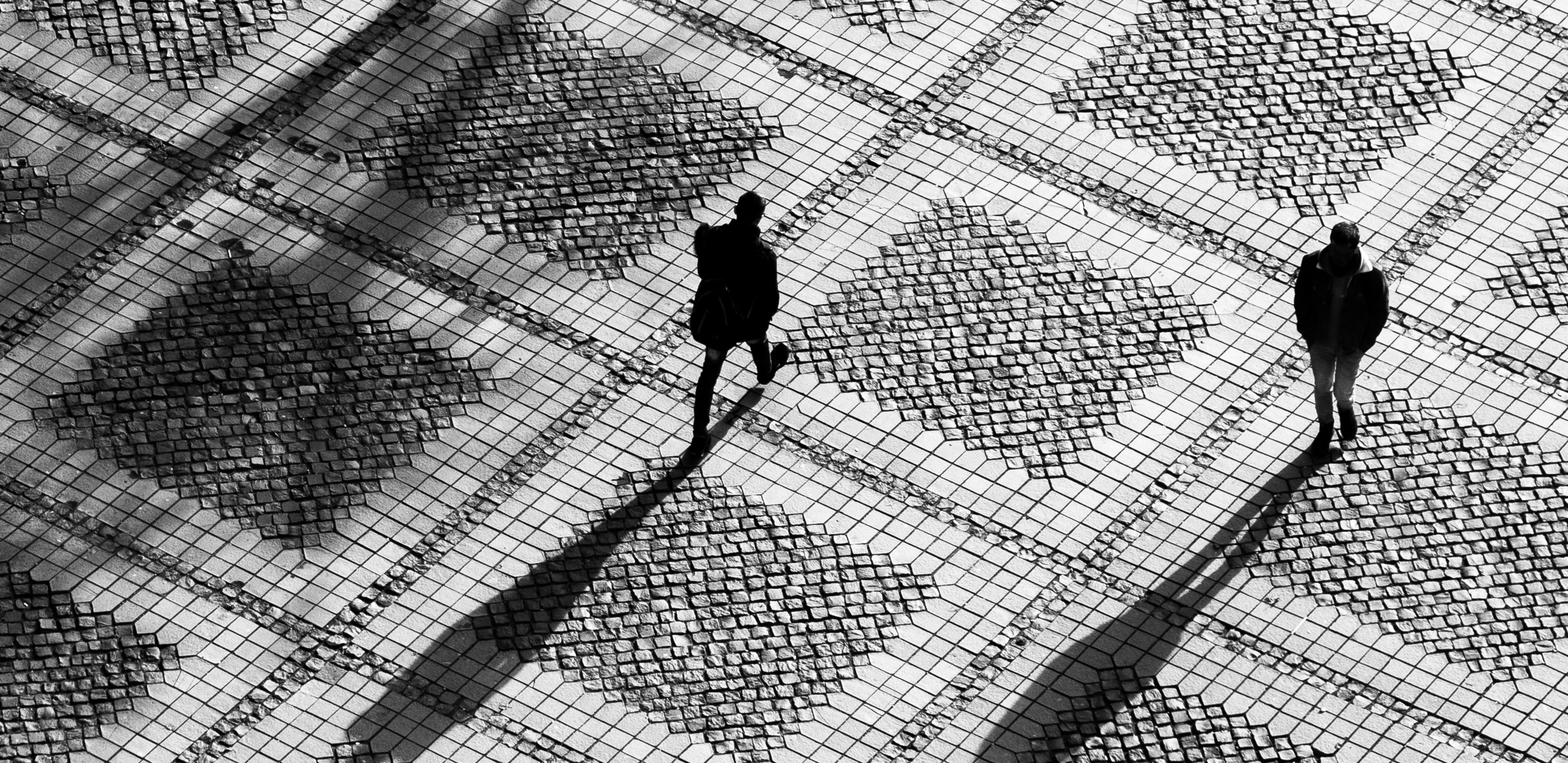 Aerial view of people walking across square, casting long shadows