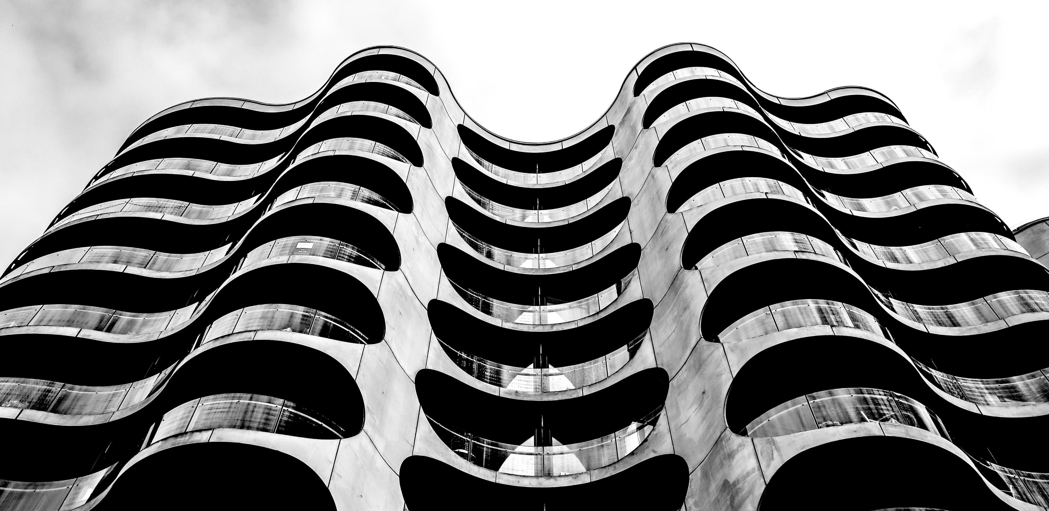 A modern building with a wave design and balconies on every floor.