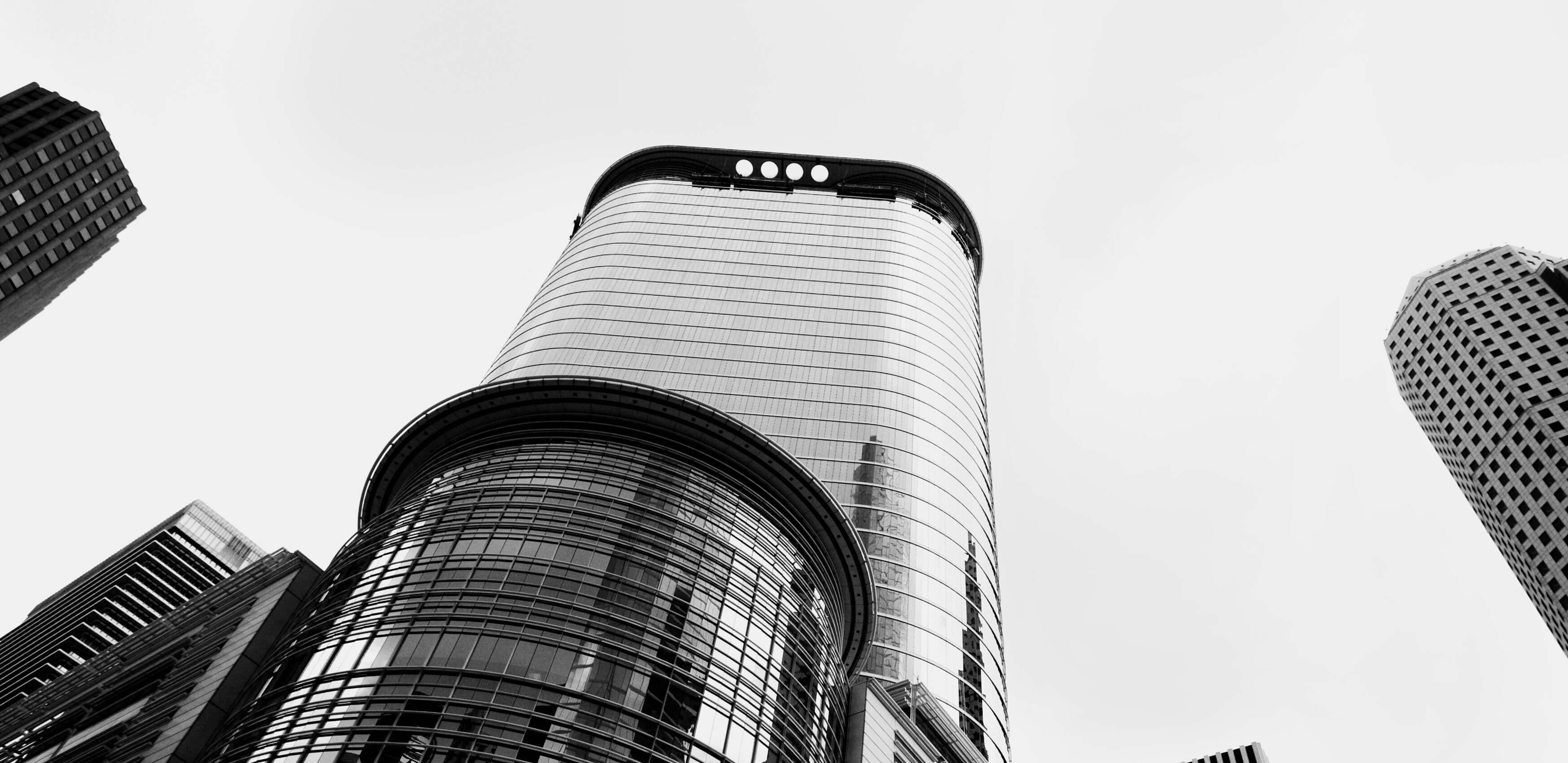 A photo from the ground level upwards to sky scrapers showing reflections of other lage buildings