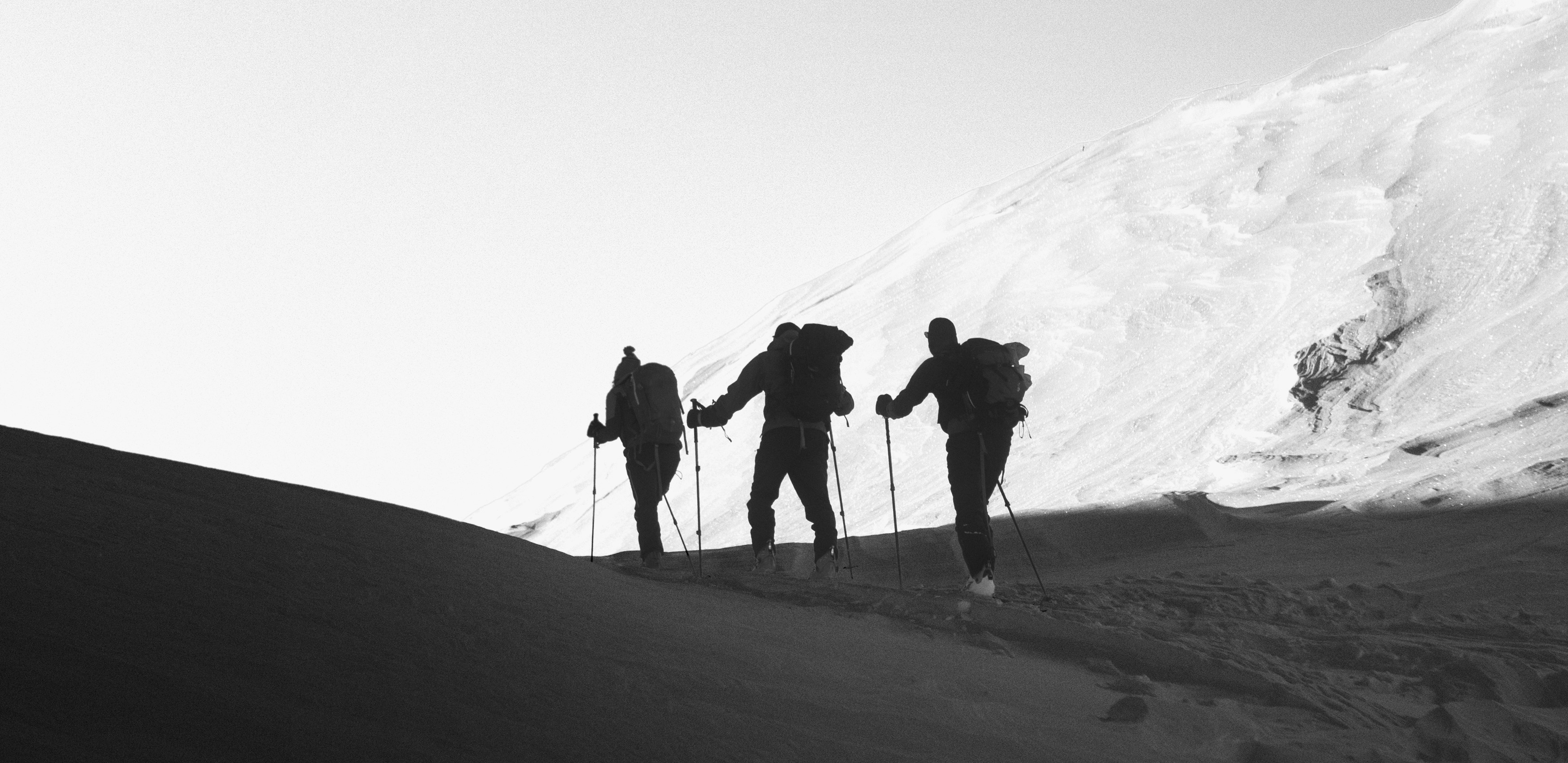 Three walkers, in snowy mountains with backpacks and walking poles