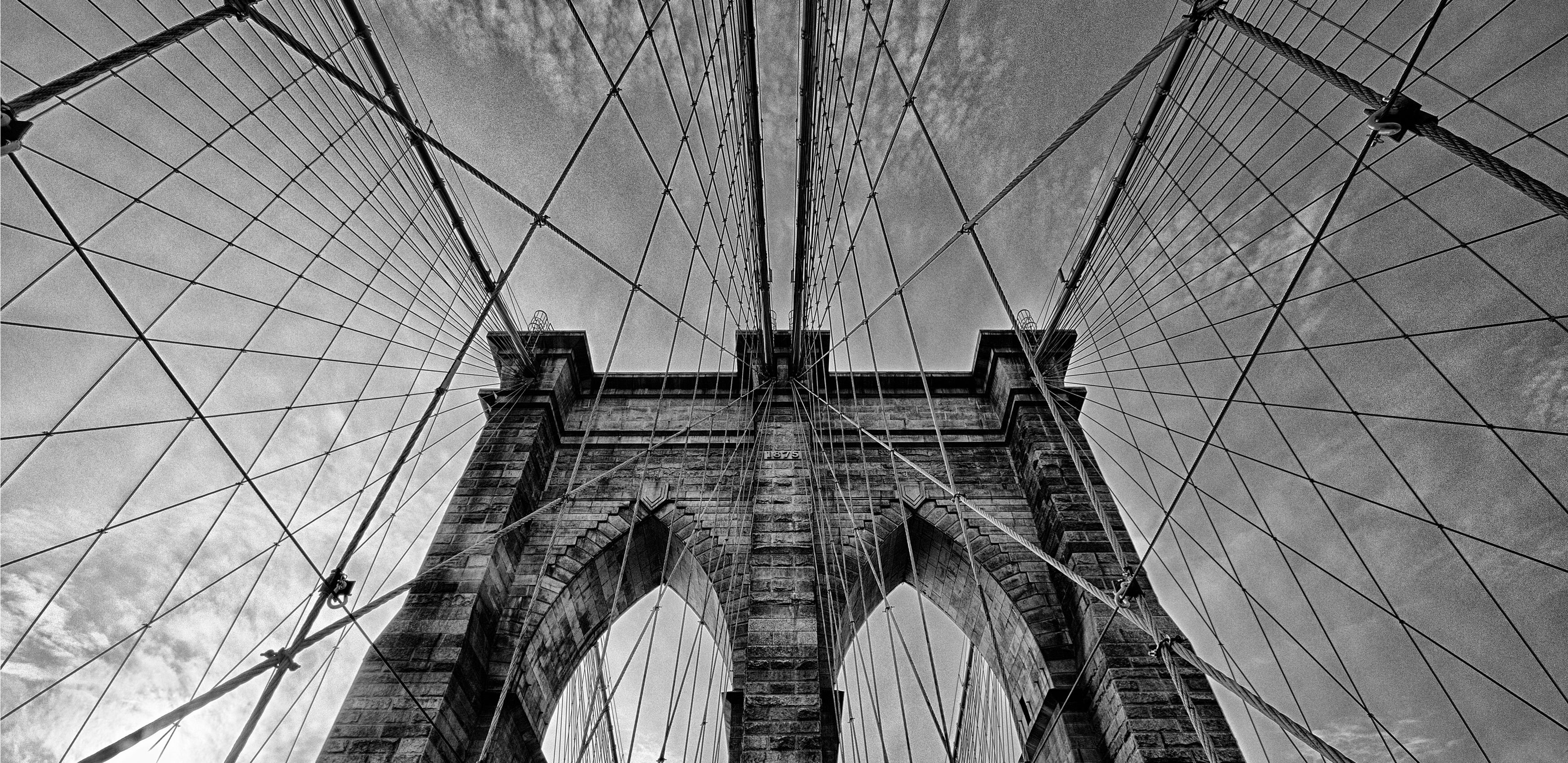 The top of a bridge with many metal beams and a large arch