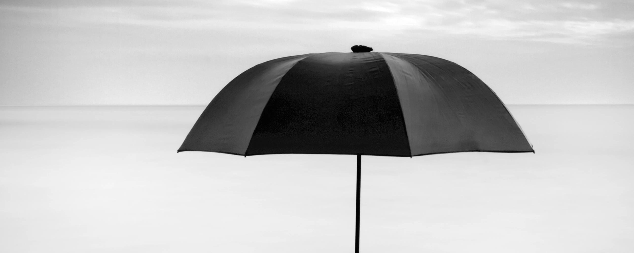 A umbrella standing up in the middle of a body of water