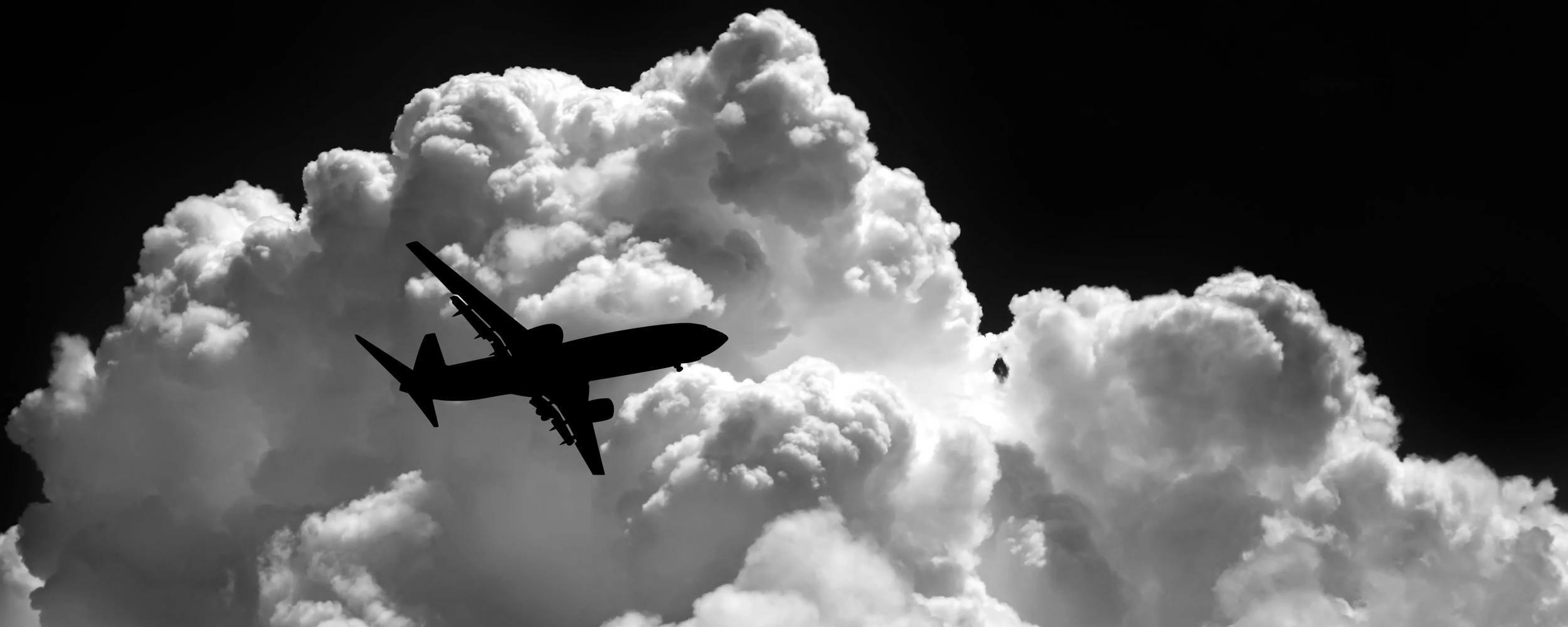 A airplane silhouette in front of a white cloud