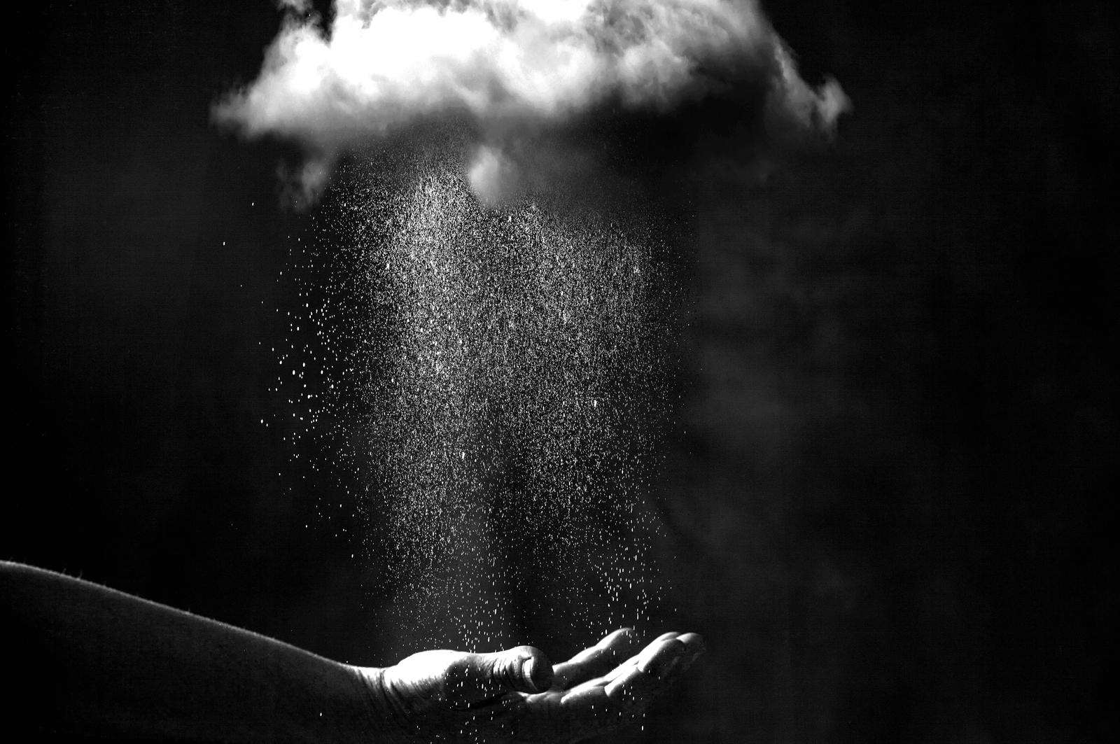 Hand underneath cloud with rain coming down