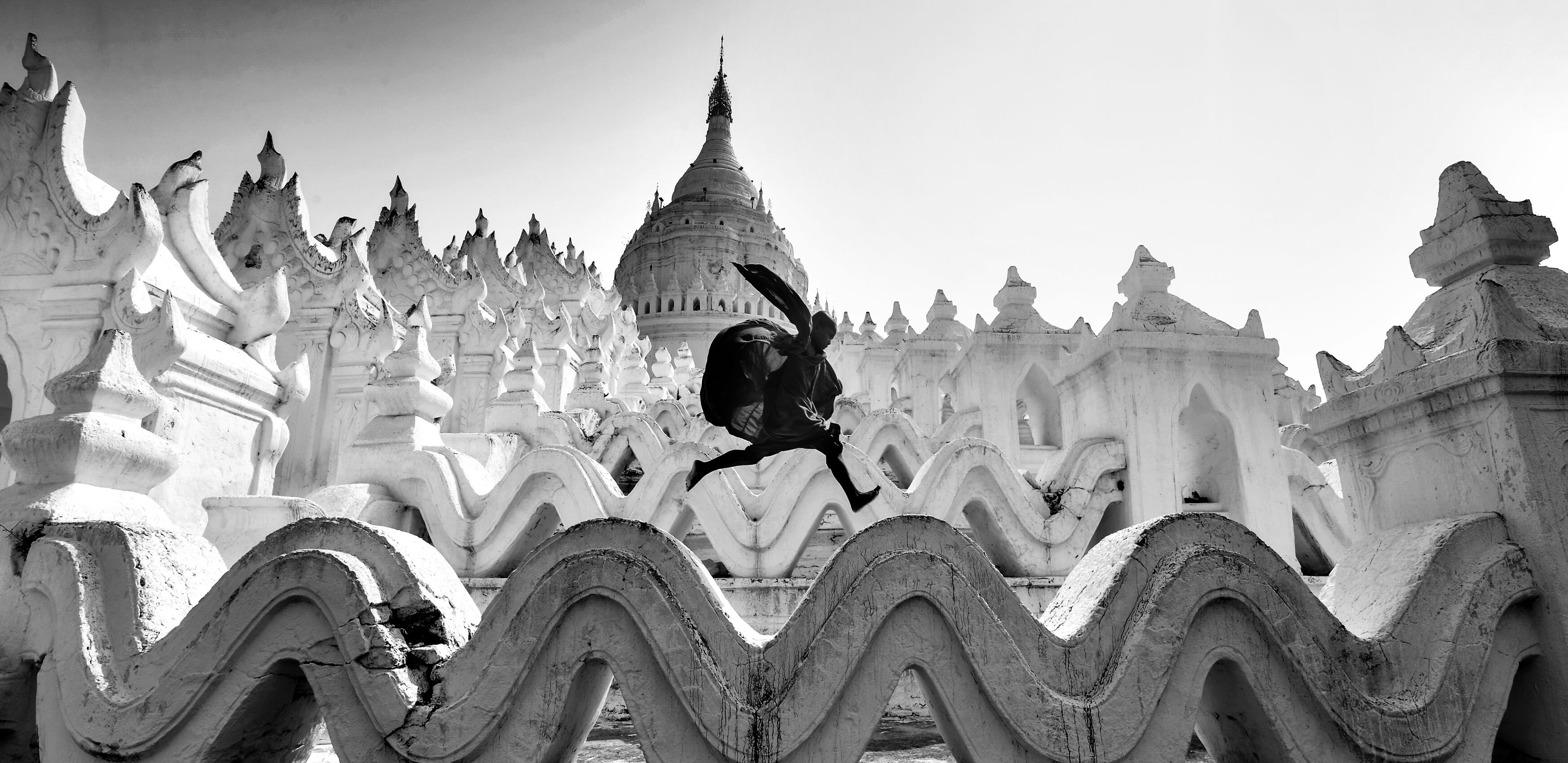 A boy jumping along a wall of an Asian style religious building