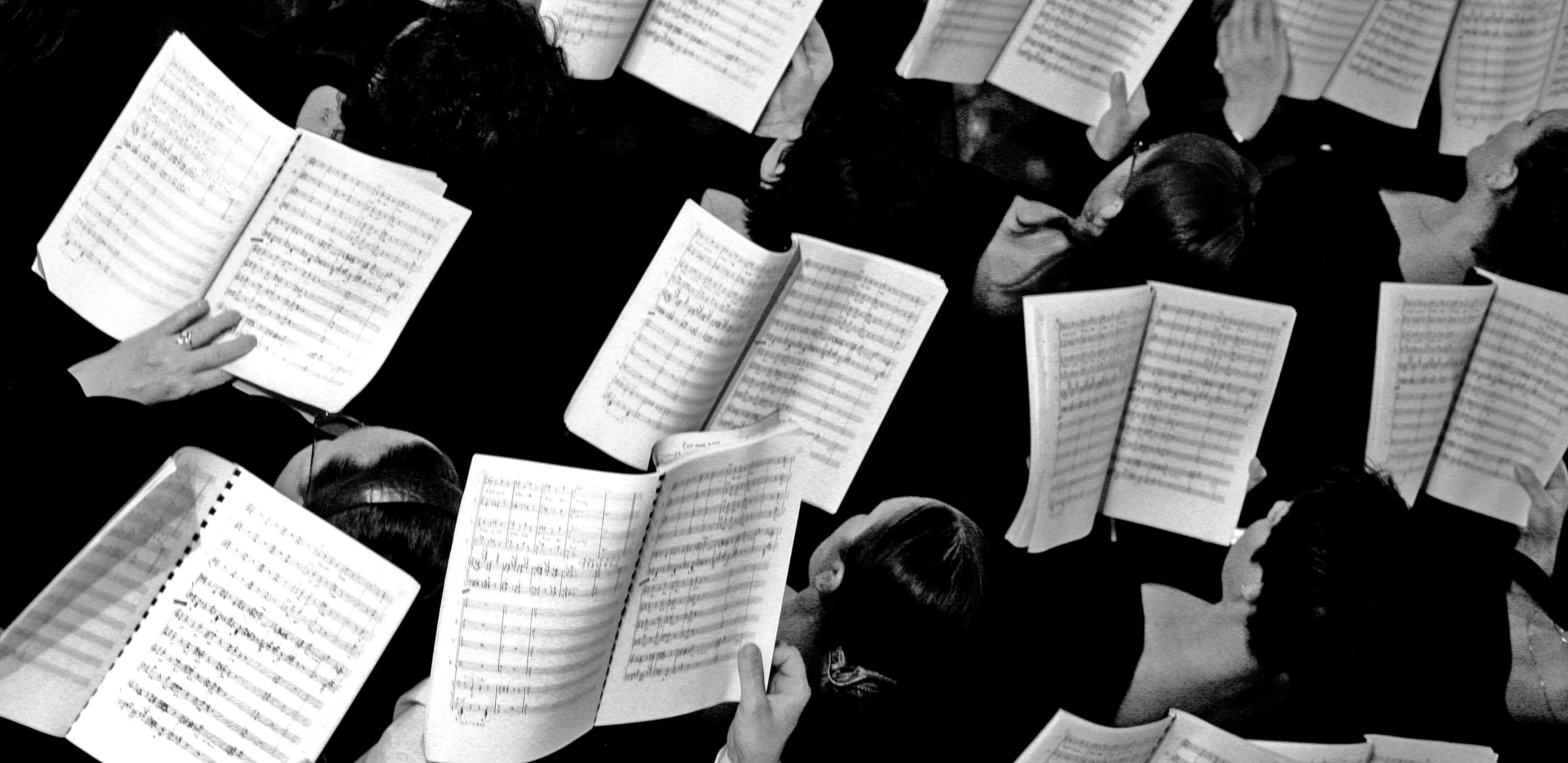 Multiple sheets of music being held, by musicians, from above