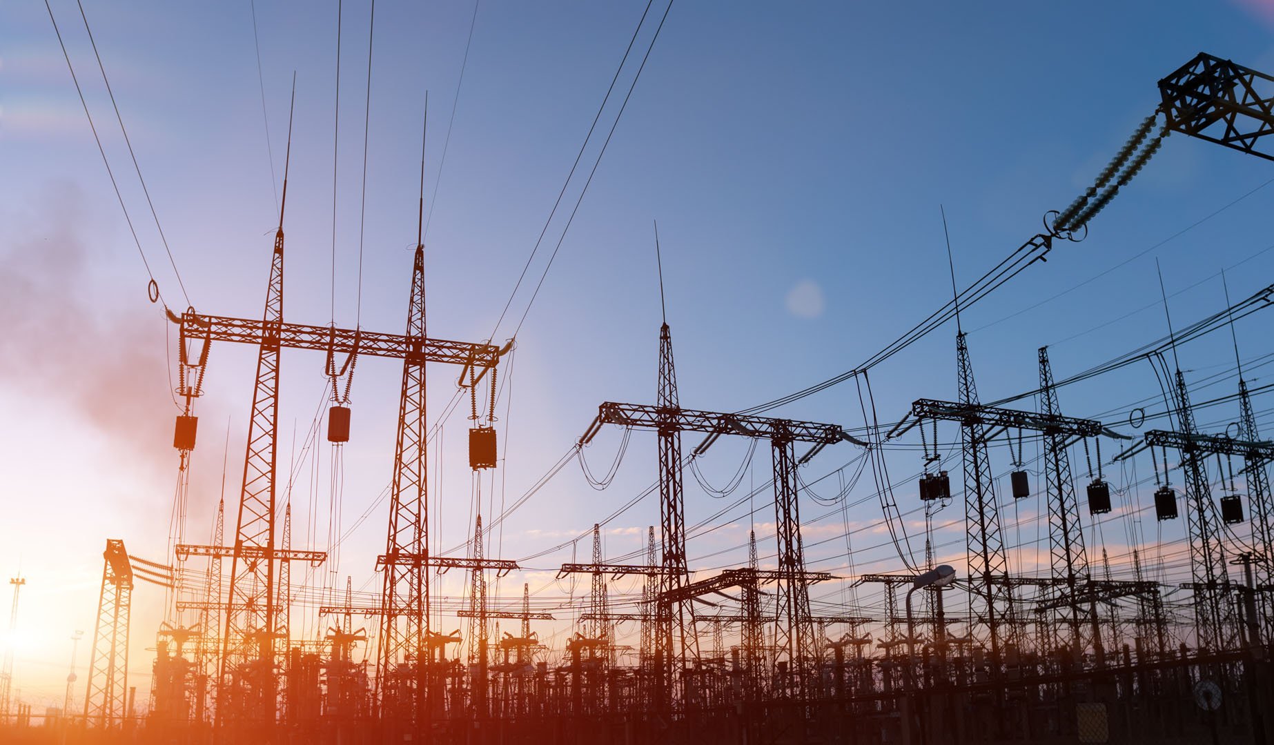 A large power substation stands against a bright, clear, sky.