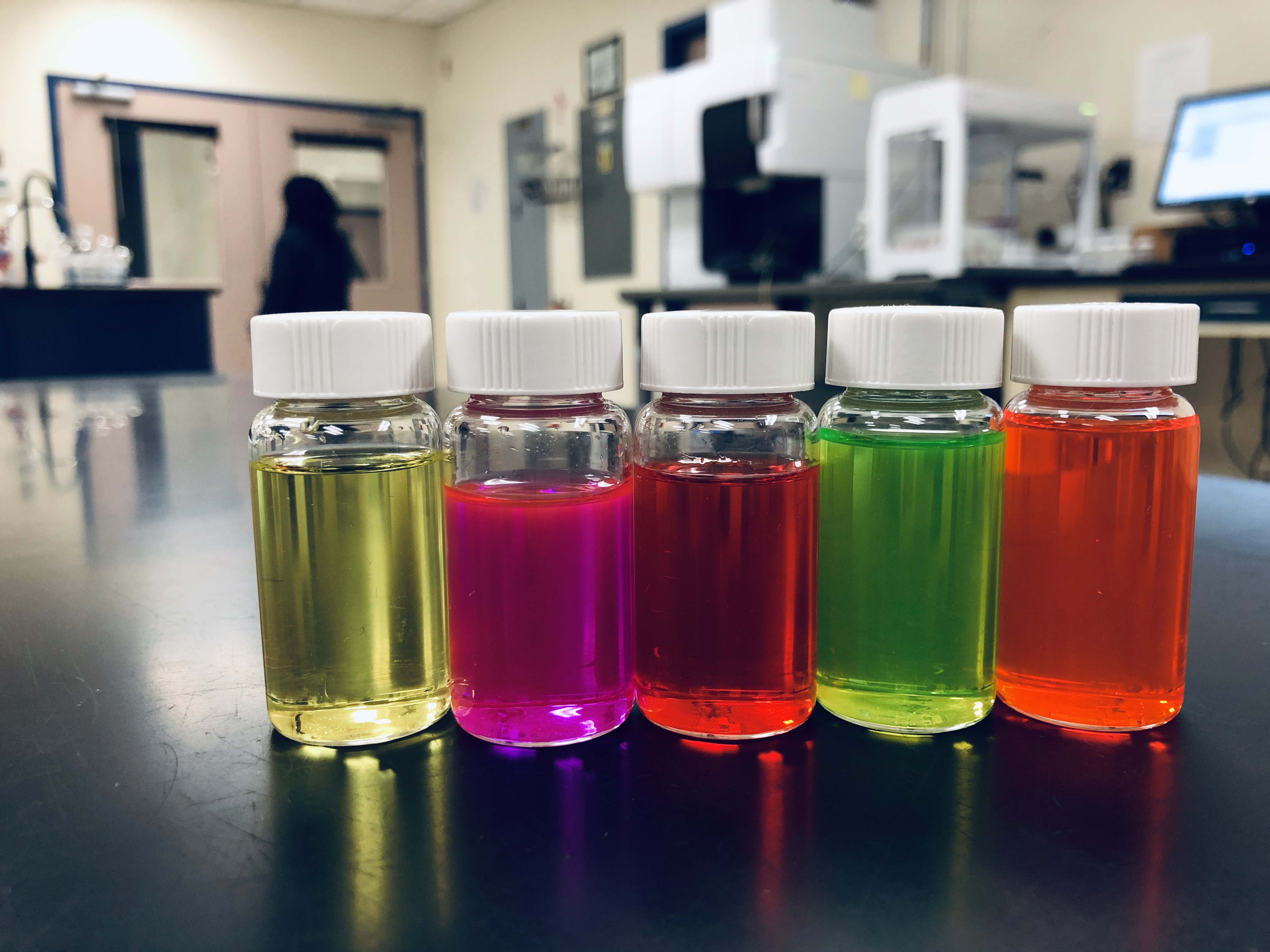 Five vials of different colored liquids are lined up on a table, likely for the purpose of lab testing.