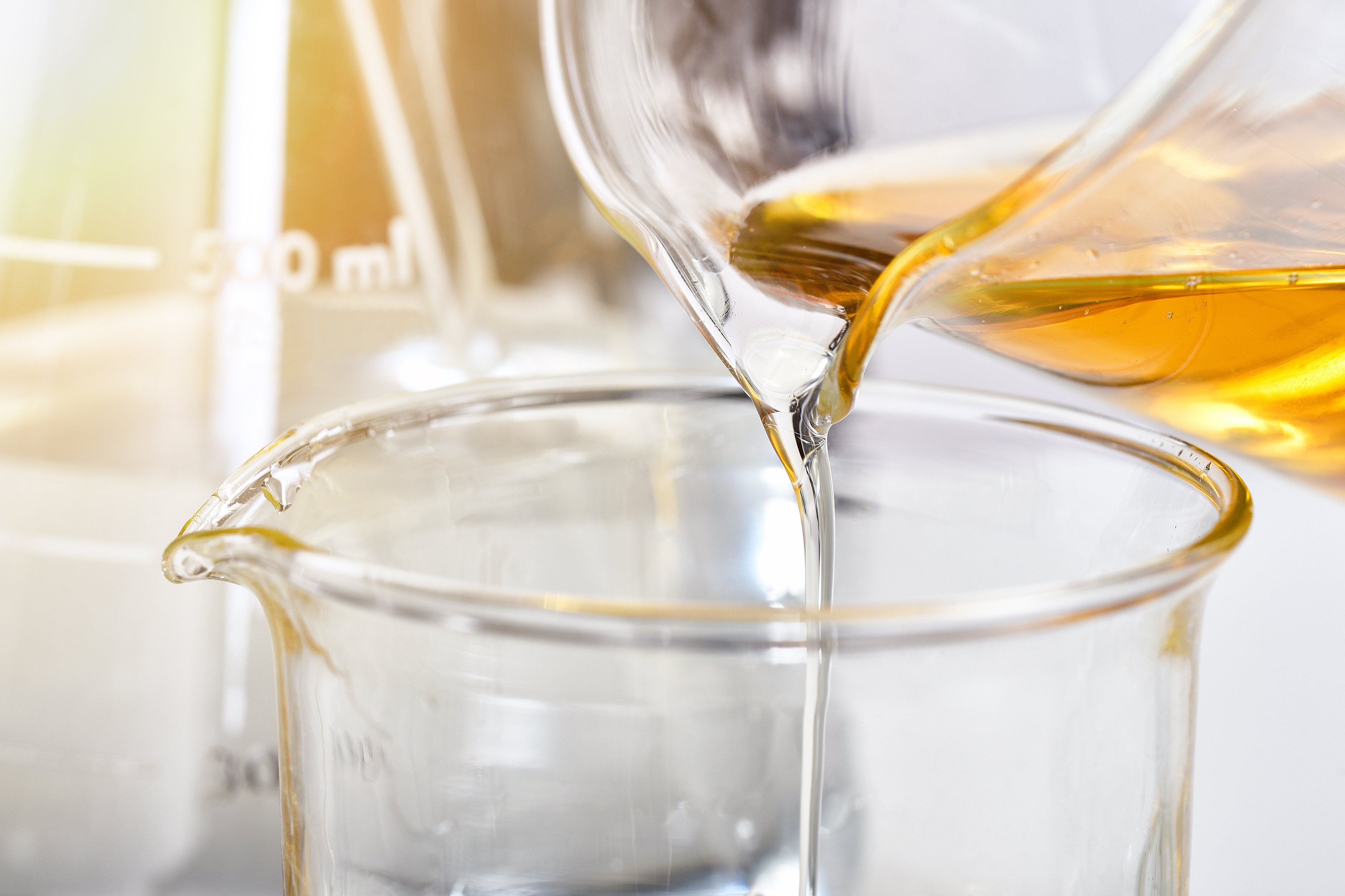 A clear liquid is being poured into a beaker from a container.