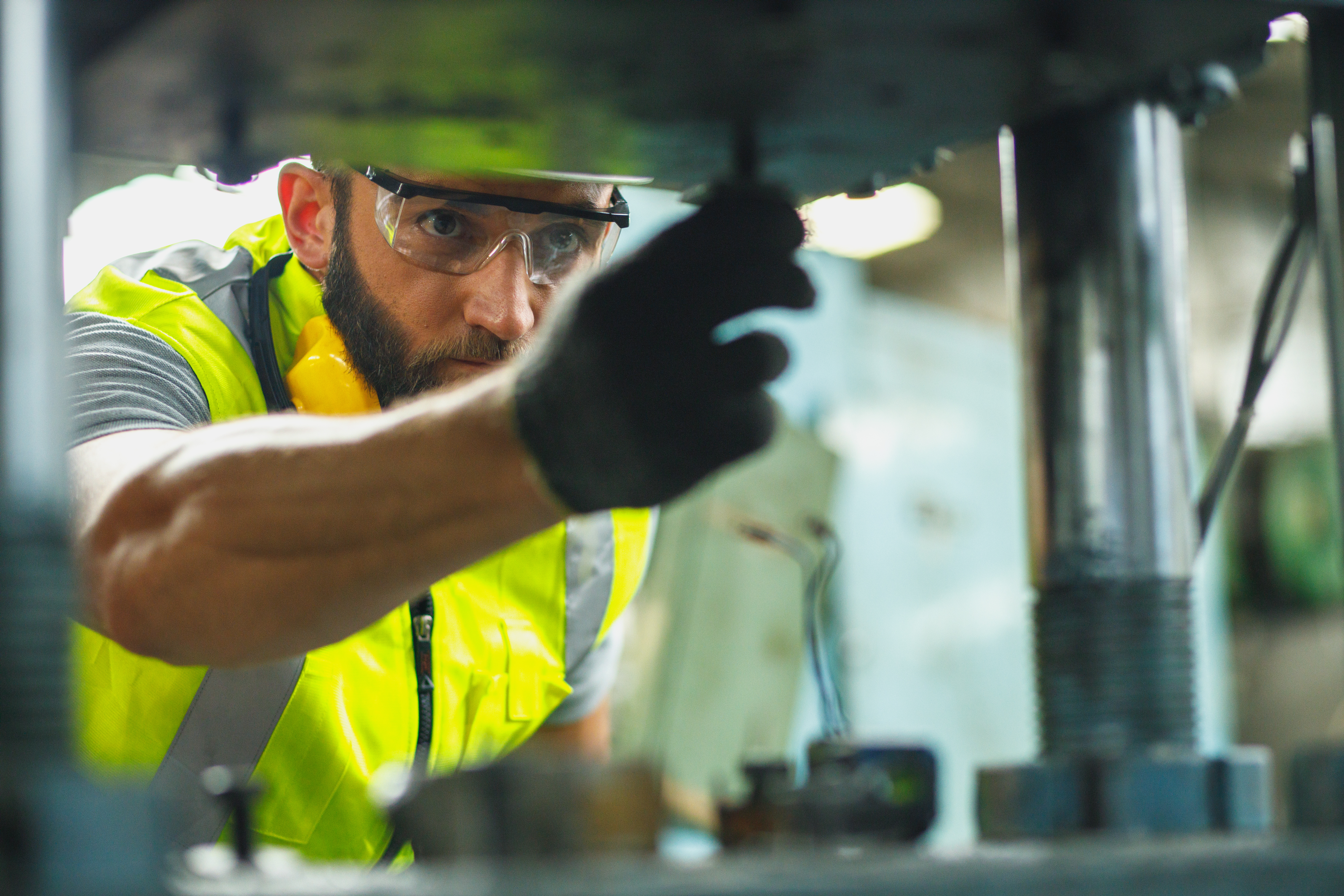 A worker in a safety vest and goggles carefully operates heavy machinery.