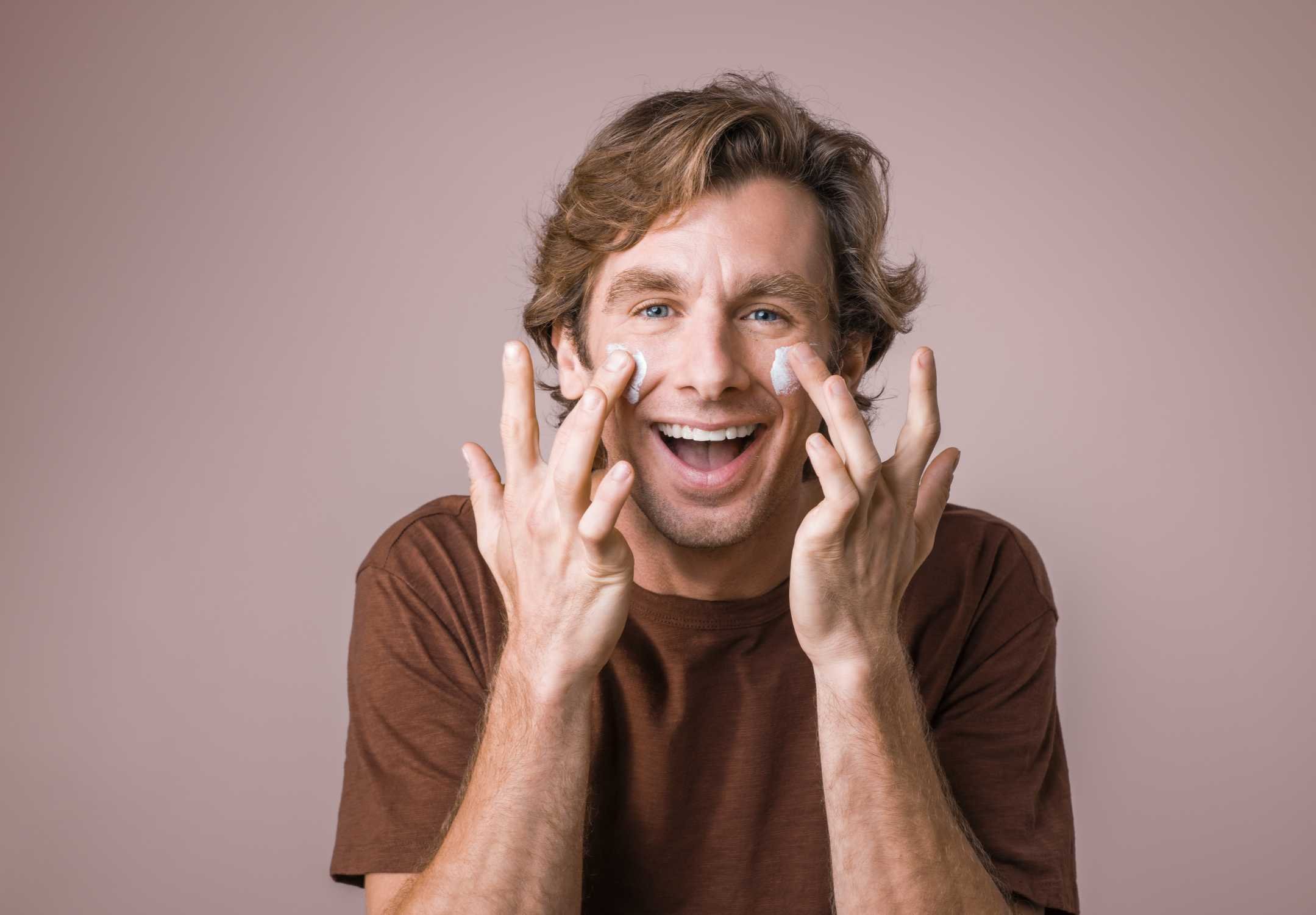 Clinical testing panelist applying cream to both cheeks on his face