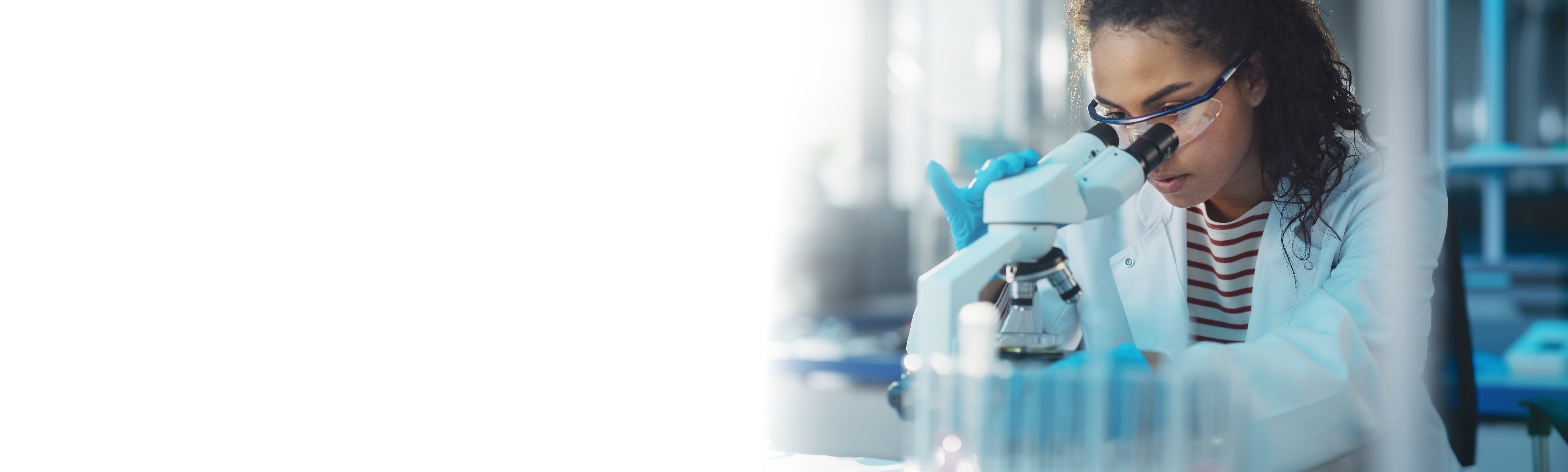 A woman in a lab coat is conducting a test using a microscope.