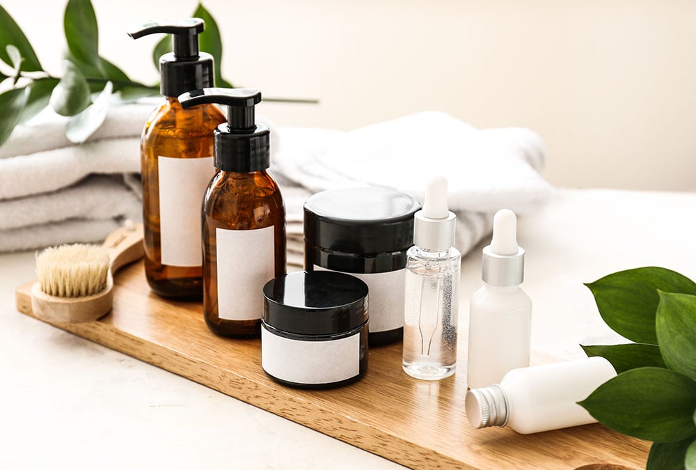The image is of a wooden tray with a variety of organic skincare products.