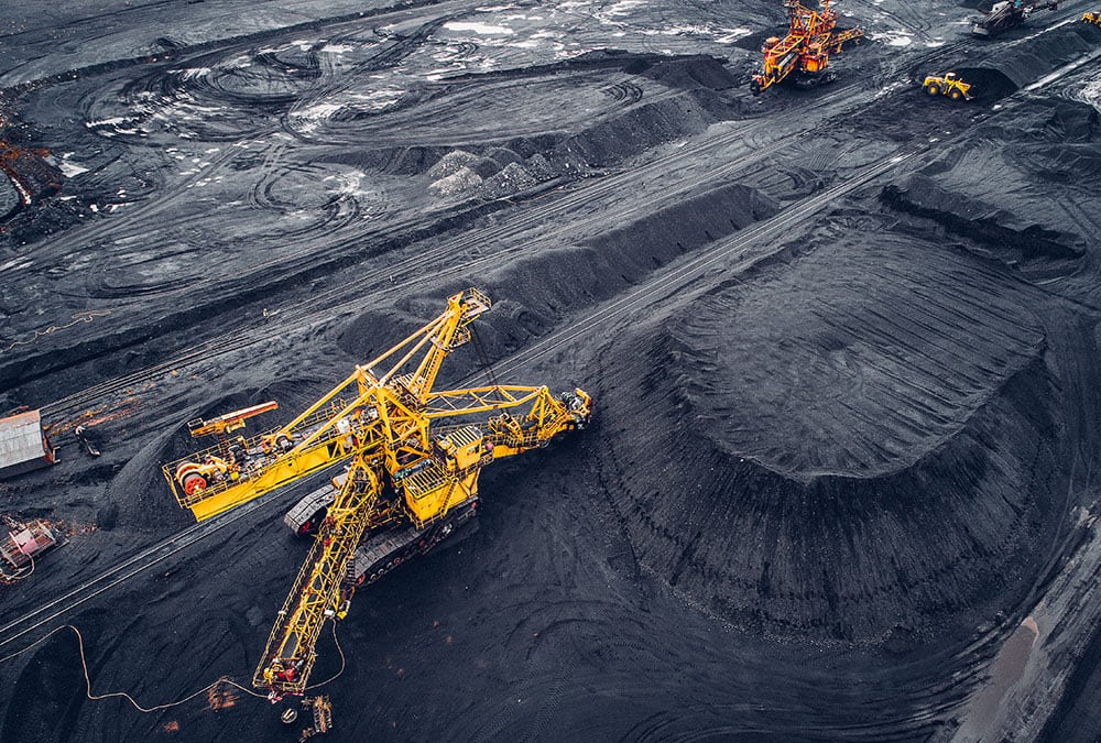 A large yellow mining machine digs coal in a mine.