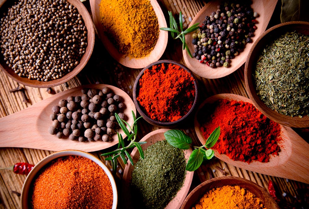 The image showcases various spices, including paprika, turmeric, coriander, and dried herbs in bowls and spoons.