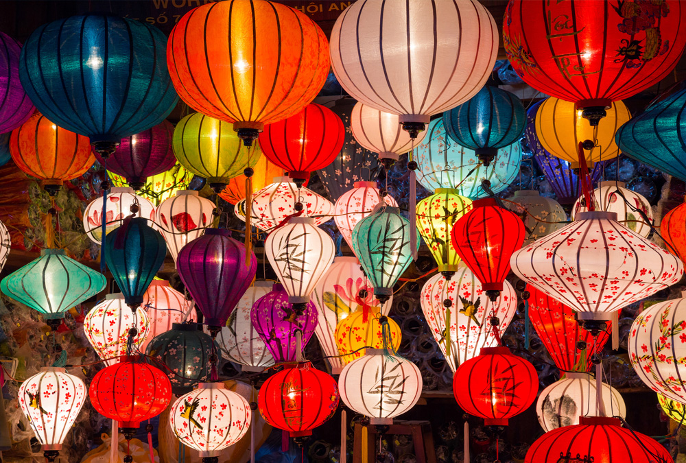 A vibrant display of colorful paper lanterns illuminates a night market, creating a festive and celebratory atmosphere.