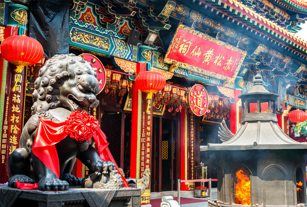 This image shows a colorful, ornate temple with incense burning in a large brazier.