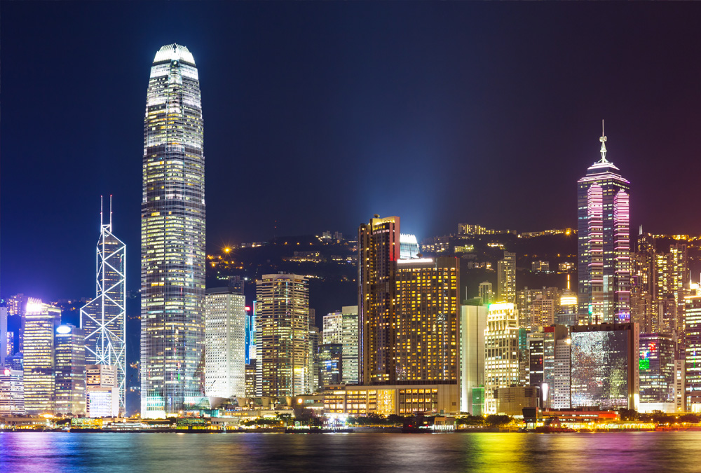 A cityscape at night with tall buildings and lit up windows.