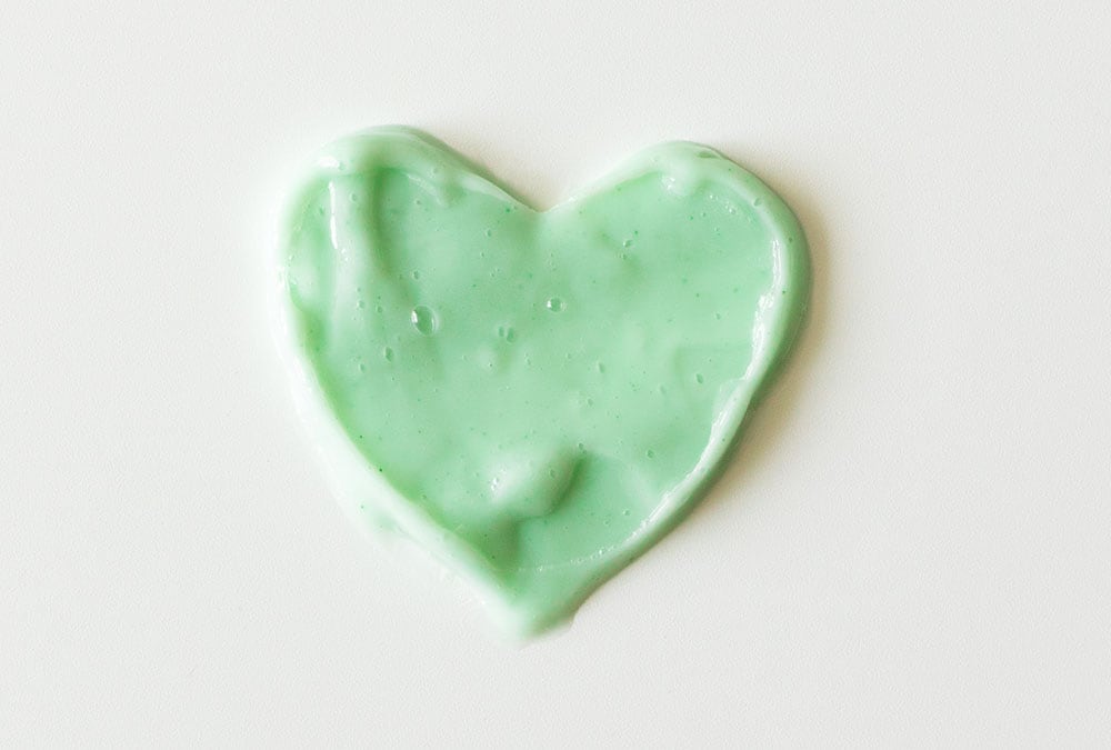 A green heart-shaped smear is on a white surface.