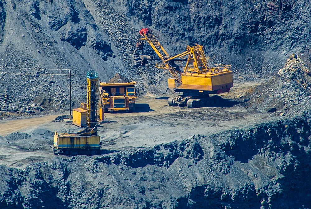 Heavy mining equipment excavates and processes ore in an open pit mine.