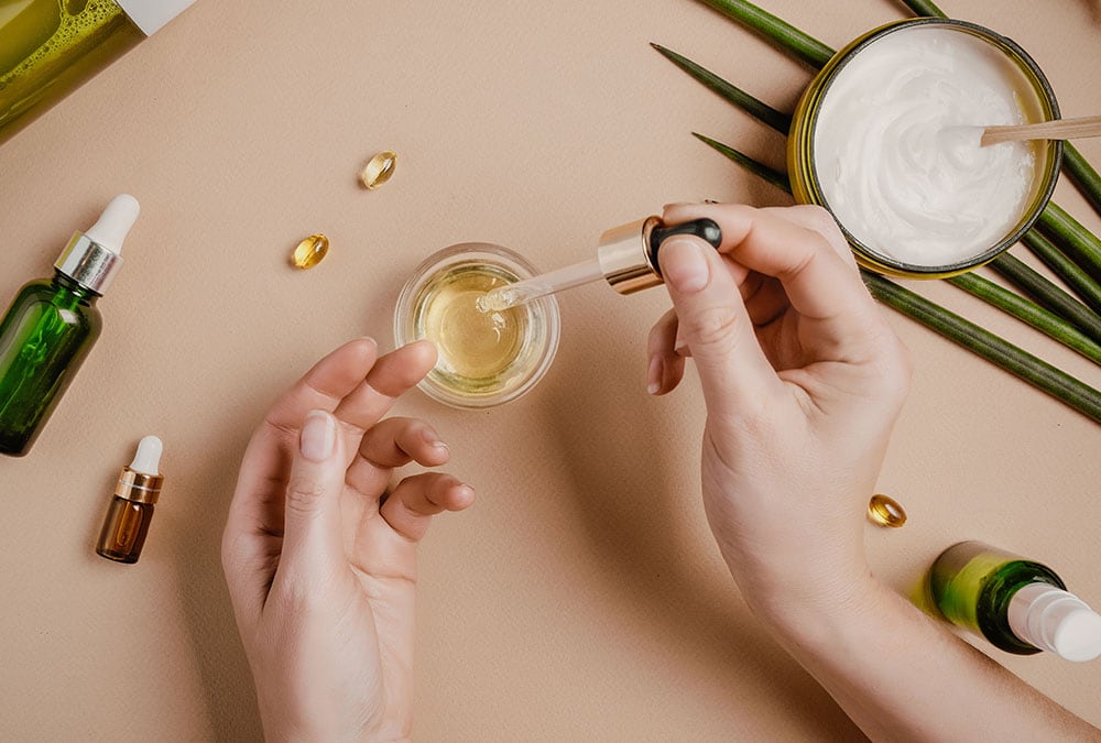 A person is applying a serum to a small dish of liquid with a dropper.
