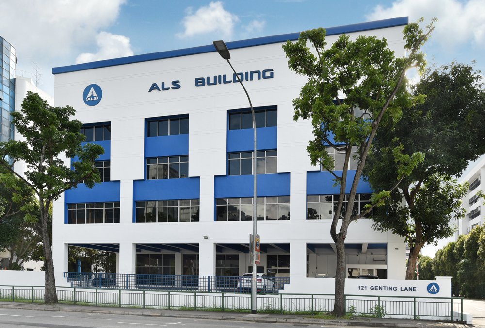 The image shows a building with "ALS BUILDING" on the front, next to the street and a sign that reads