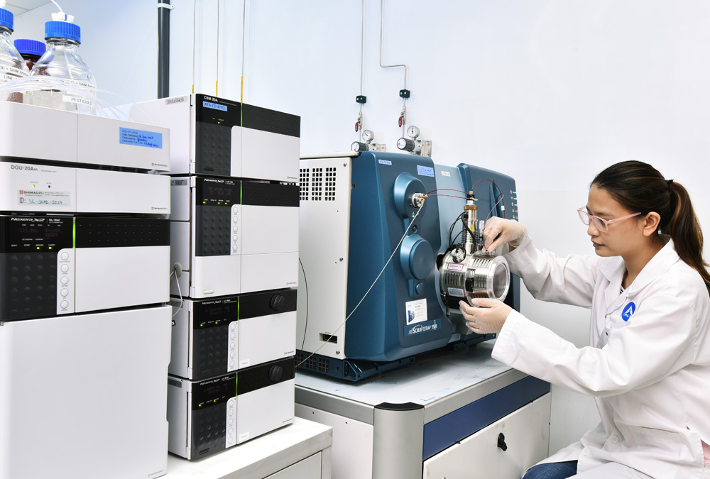 A scientist is carefully working with a high performance liquid chromatography system to perform analysis.