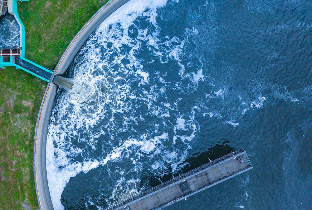 An aerial picture of water flowing into a large, circular basin at a water treatment facility.