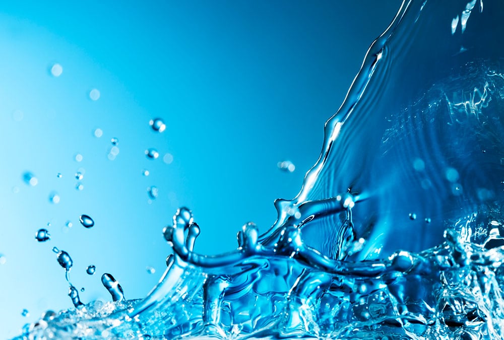 The image shows a close-up of a water splash against a blue background.