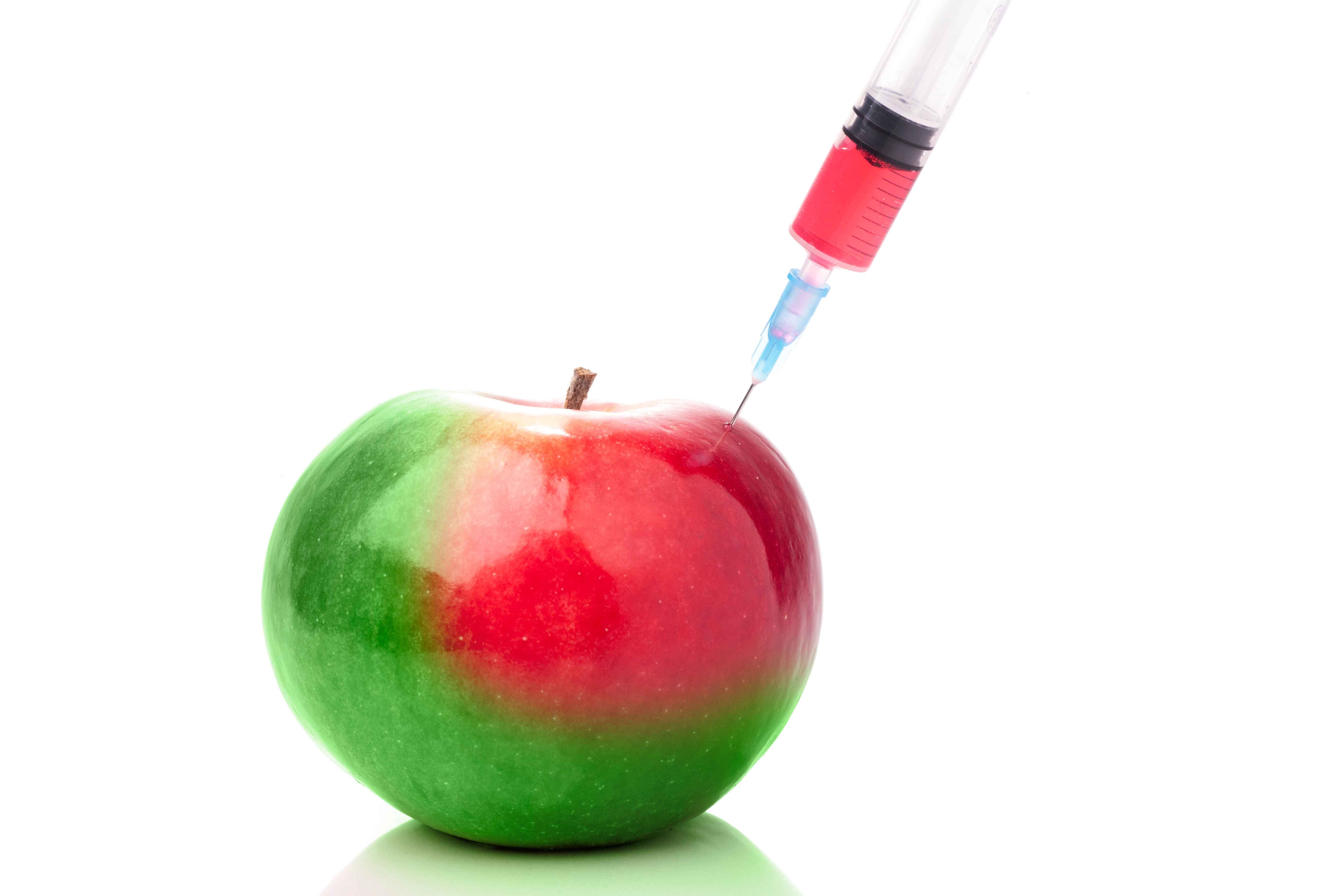 Injeção em Maçã Verde Maçã verde a ser injetada com líquido vermelho por uma seringa.