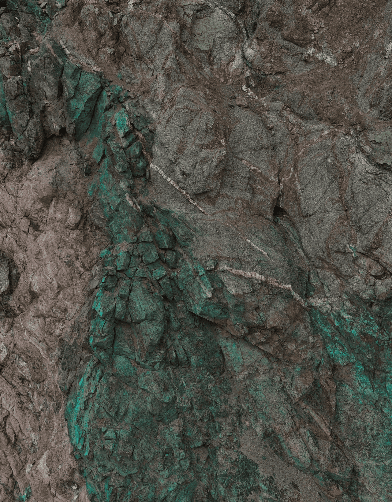 Close-up of copper-stained rock with quartz veining