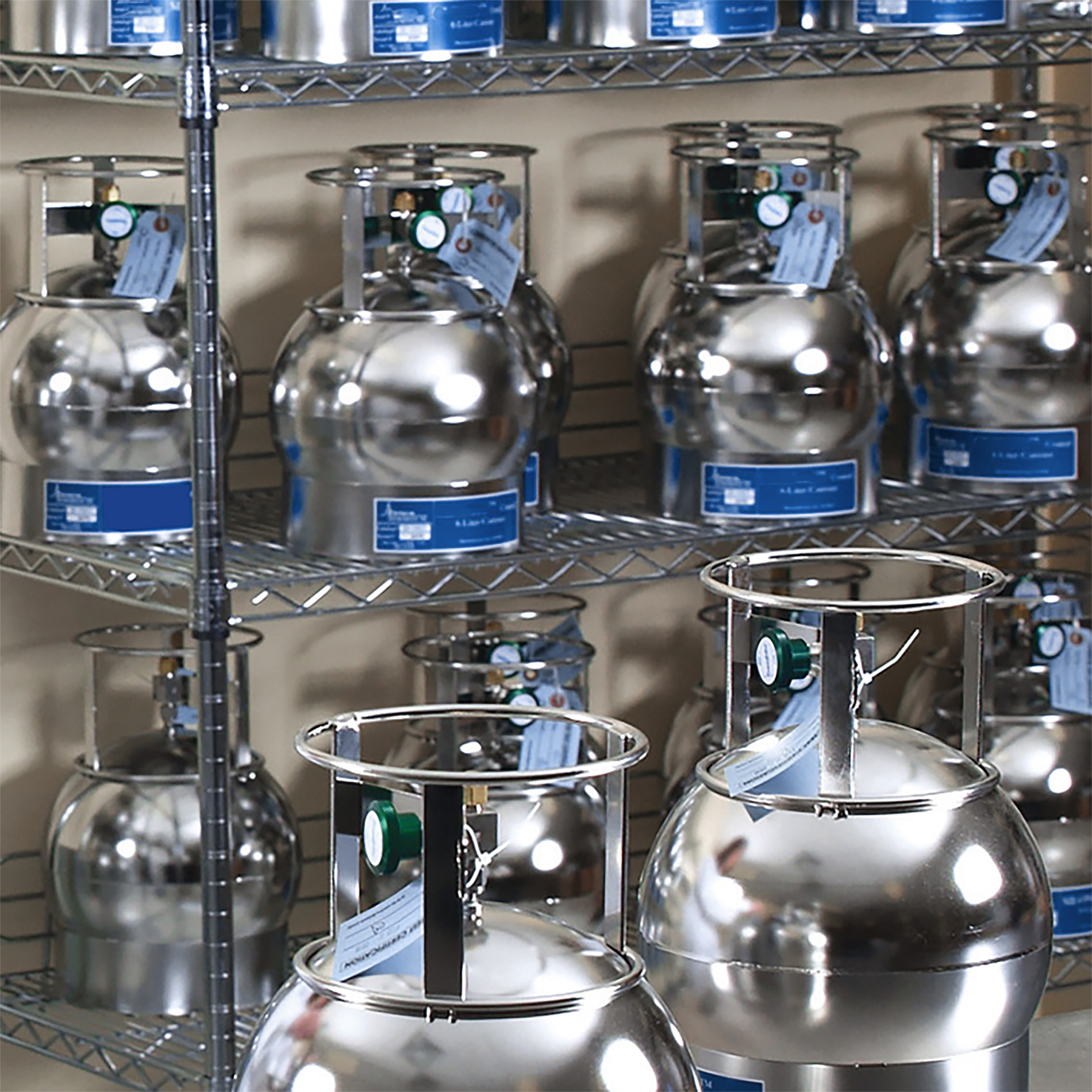 The image shows a stacked, metal industrial shelving unit holding rows of cylindrical canisters.