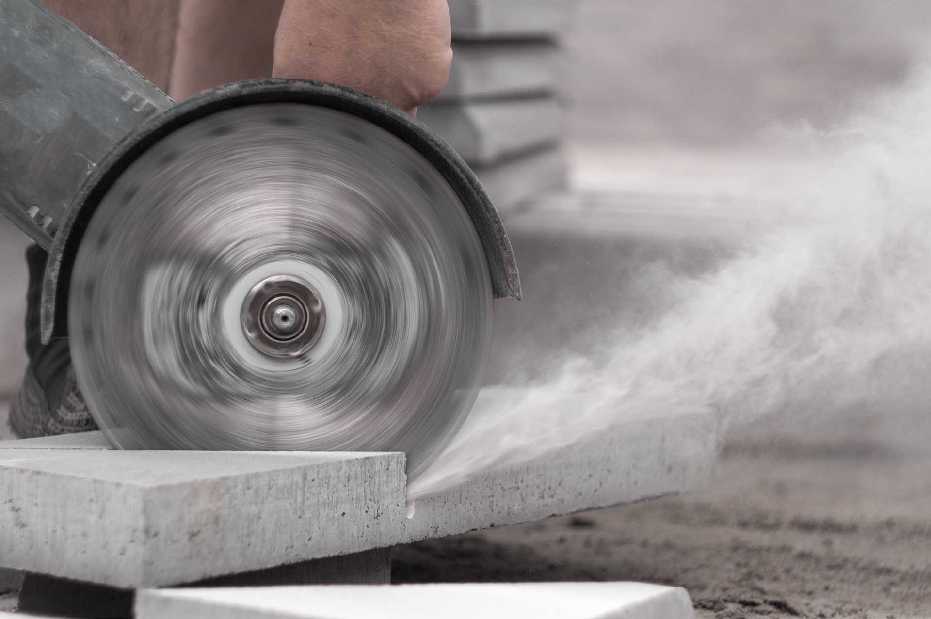A person is using a saw to cut a block of concrete.